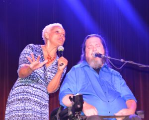 Executive Director Myrna Clayton sings on stage alongside Jazz singer Rusty Taylor (wheelchair user).