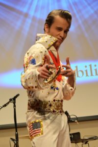 DELVIS (teen singer and Elvis Entity) poses for the camera wearing his white jumpsuit with red and blue rhinestones.