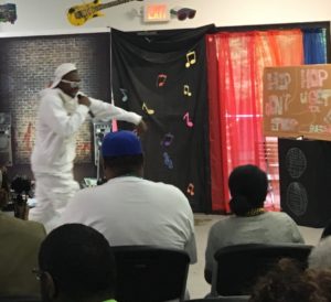 Young adult male with a developmental disability performs as a rapper with his attire matching from head to toe in all white as he entertains the audience.