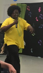 Young adult male with a developmental disability is smiling as he sings.