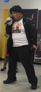 A close up photo of a young adult male with a developmental disability impersonating Michael Jackson for his talent.